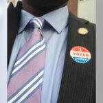 Photo of a 'vote' pin on Dr. Dumay's blazer