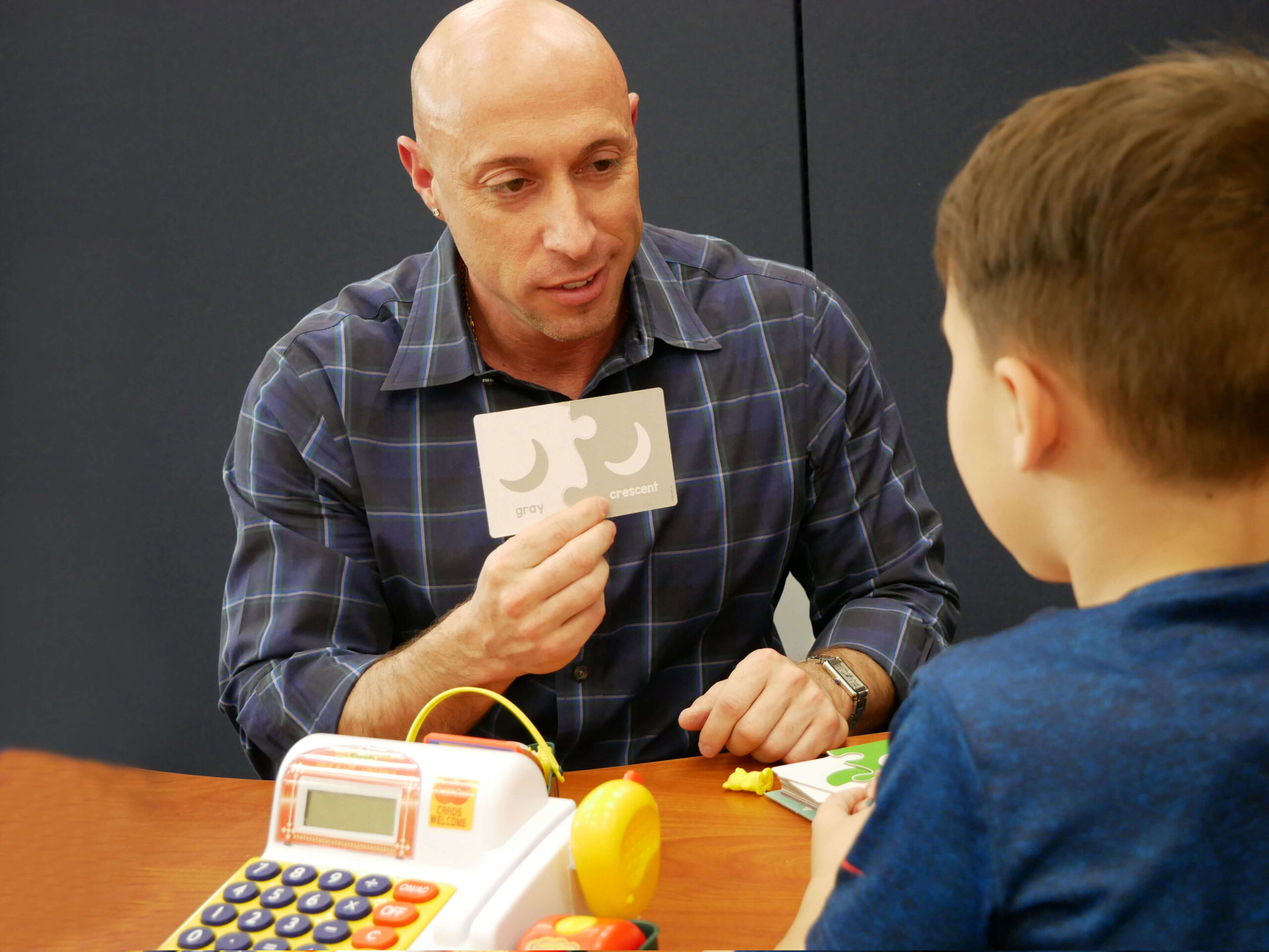 Photo of a grad student in the ASD-ABA program working with a student