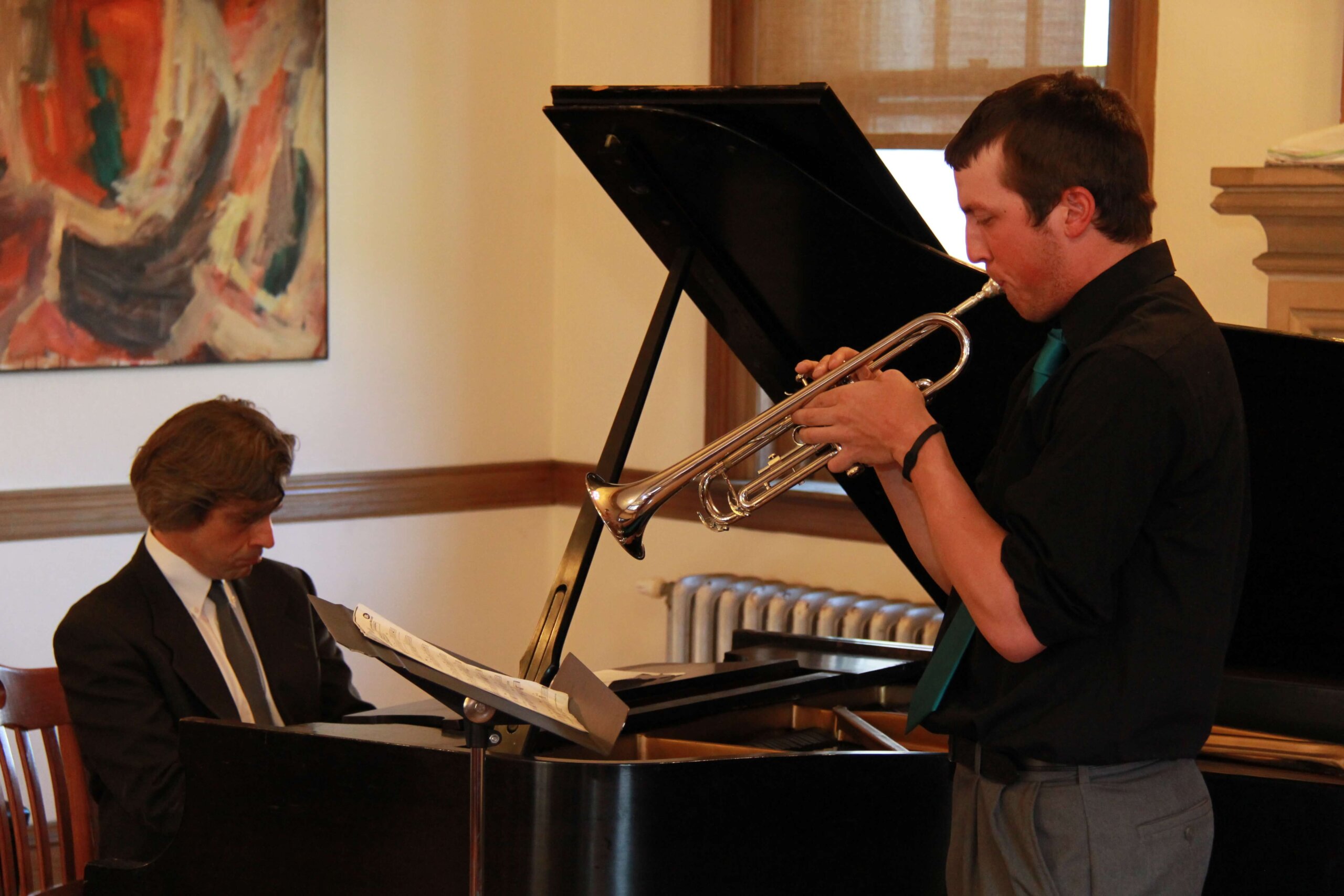 Photo of Professor Chris Bakriges playing the piano and a student playing the trumpet