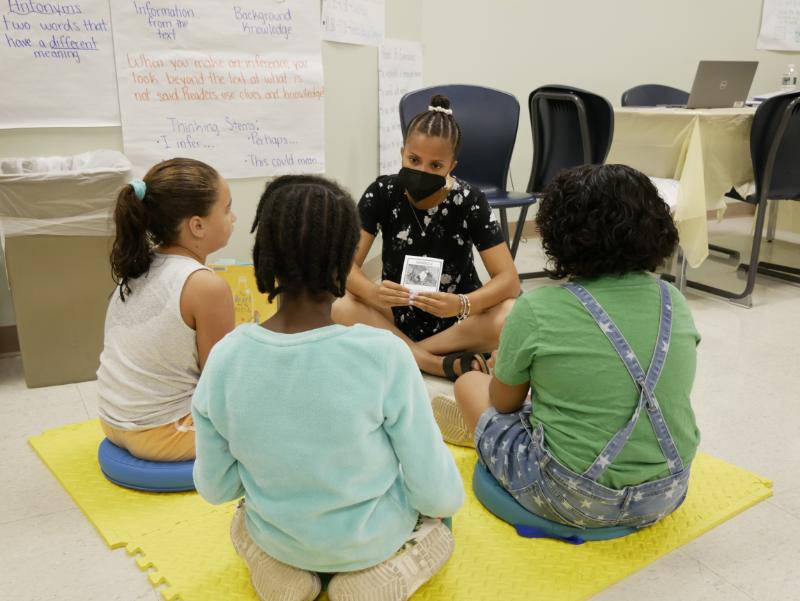 Students in a classroom, sitting on the floor