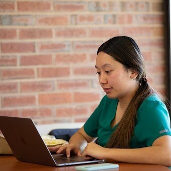 Photo of a nursing student, studying on a laptop in the library