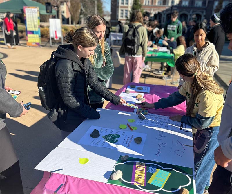 Photo of students gathered on the quad looking at items on several tables