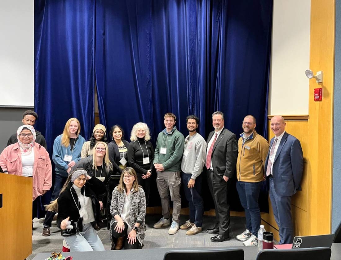 UNE - Elms College agreement. Photo of people on stage