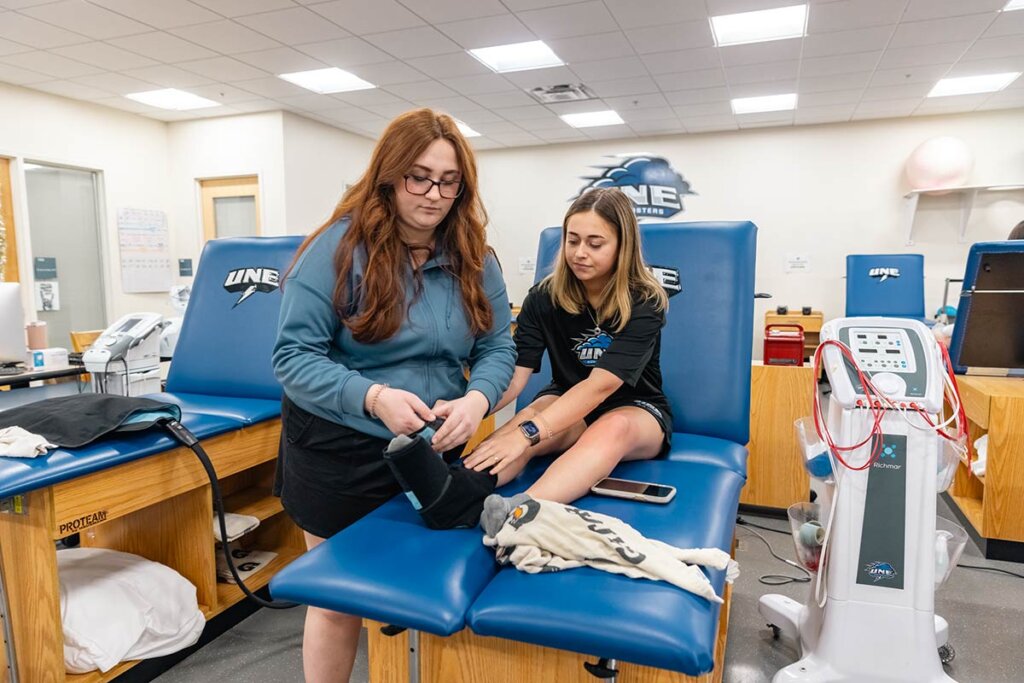 Photo of two women in a clinic, attaching a foot brace