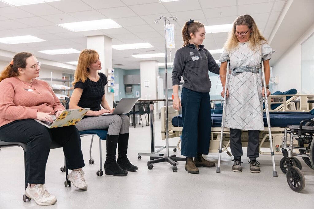 Photo of four women in a clinic setting, one woman is using crutches.