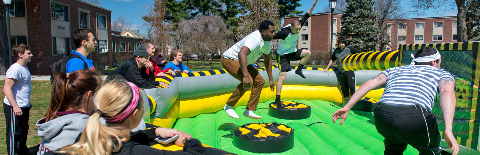 Photo of several students on the quad jumping on a lime green inflatable thing. 