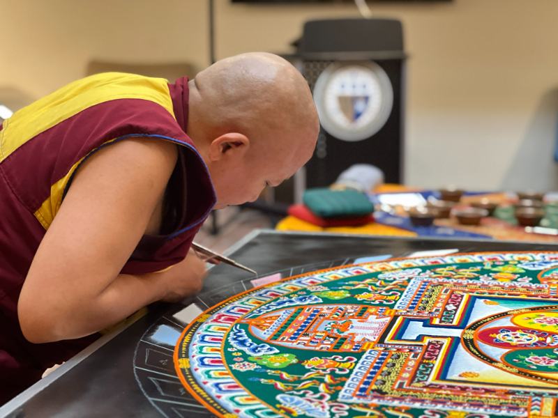 Photo of a monk working on a sand mandala
