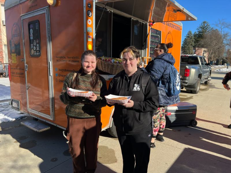 Photo of two students holding food in front of a food truck
