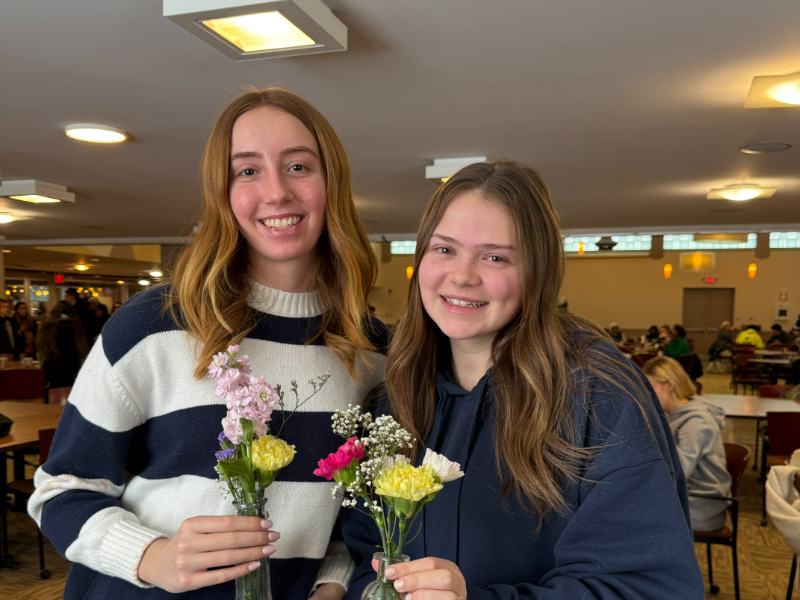 Photo of two students holding flowers