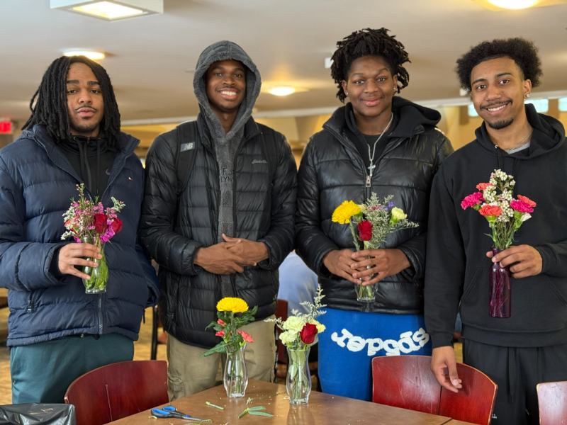 Photo of four students holding flowers