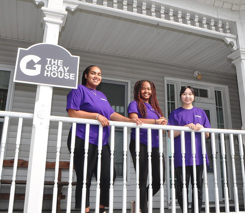 Photo of 3 women standing on the porch of The Gray House