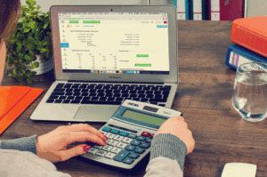 Person using a calculator and a laptop