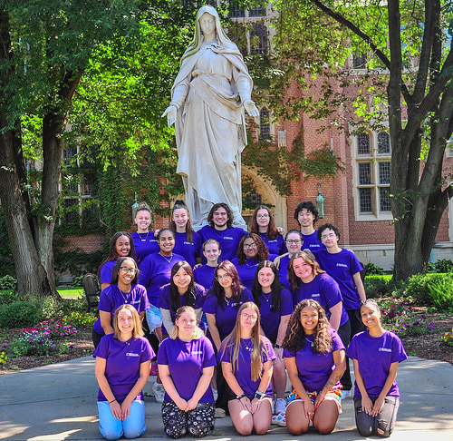 Photo of a group of 21 students in front of the Mary statue at Elms College