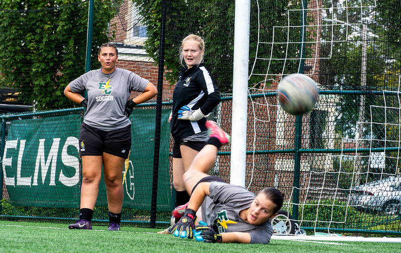 3 student athletes, goalie diving 