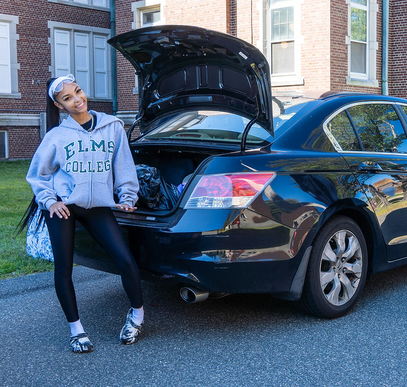 student arrives at Elms College, unloading trunk of a black car