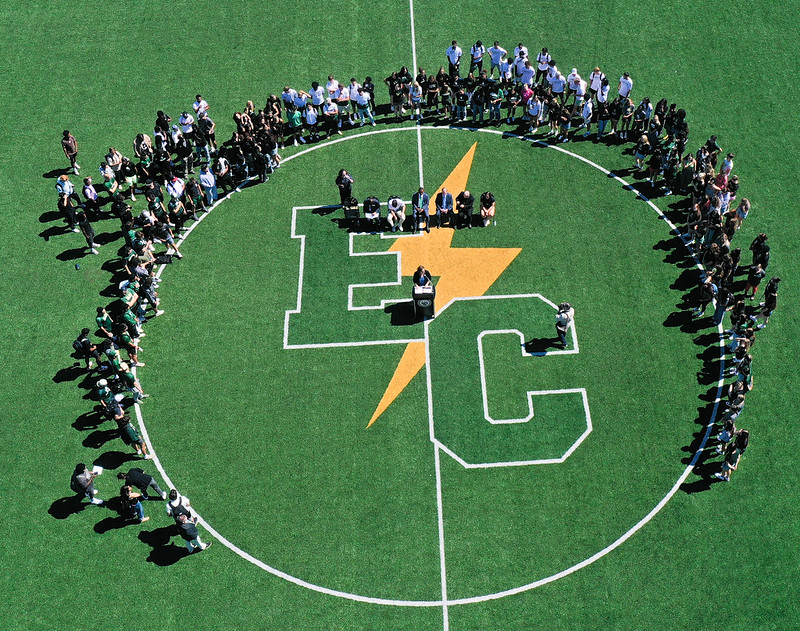 Many students gather on the athletic field around the EC logo 